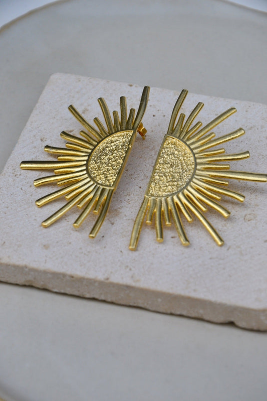 Boucles d'Oreilles Aurora – L’éclat d’un lever de soleil éternel
Les Boucles d'Oreilles Aurora capturent la magie lumineuse des premières lueurs de l’aube. Inspirées par la déesse grecque Éos, incarnation de l’aurore, ces boucles offrent un design captivant avec des rayons dorés qui évoquent la douceur et la force d’un nouveau jour. Parfait mélange d’élégance et de symbolisme, elles illuminent chaque tenue d’un éclat intemporel.