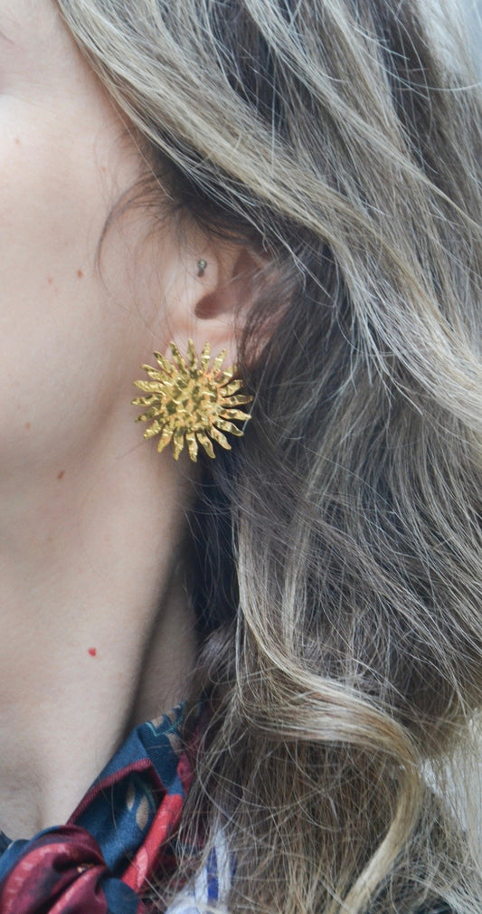 Boucles d'oreilles plaquées or 18K, en forme de soleil, faites main par nos artisans.  
Dans la mythologie grecque, Hélios (en grec ancien Ἥλιος) est le dieu du Soleil, souvent représenté avec une couronne rayonnante. 