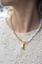 Collier Galene – Chaîne Dorée, Perles Blanches &amp; Lune Dorée

Laissez-vous envelopper par la douceur et l'élégance du collier "Galene", inspiré de la nymphe grecque de la sérénité marine. Ce bijou délicat allie la pureté des perles blanches à l’éclat d’une chaîne dorée et d’un pendentif lune dorée, symbole de calme, de féminité et d’intuition.

Pensé comme un hommage à la tranquillité de la mer et à la lumière lunaire, le collier "Galene" apporte une touche de grâce naturelle à toutes vos tenues. Parfait