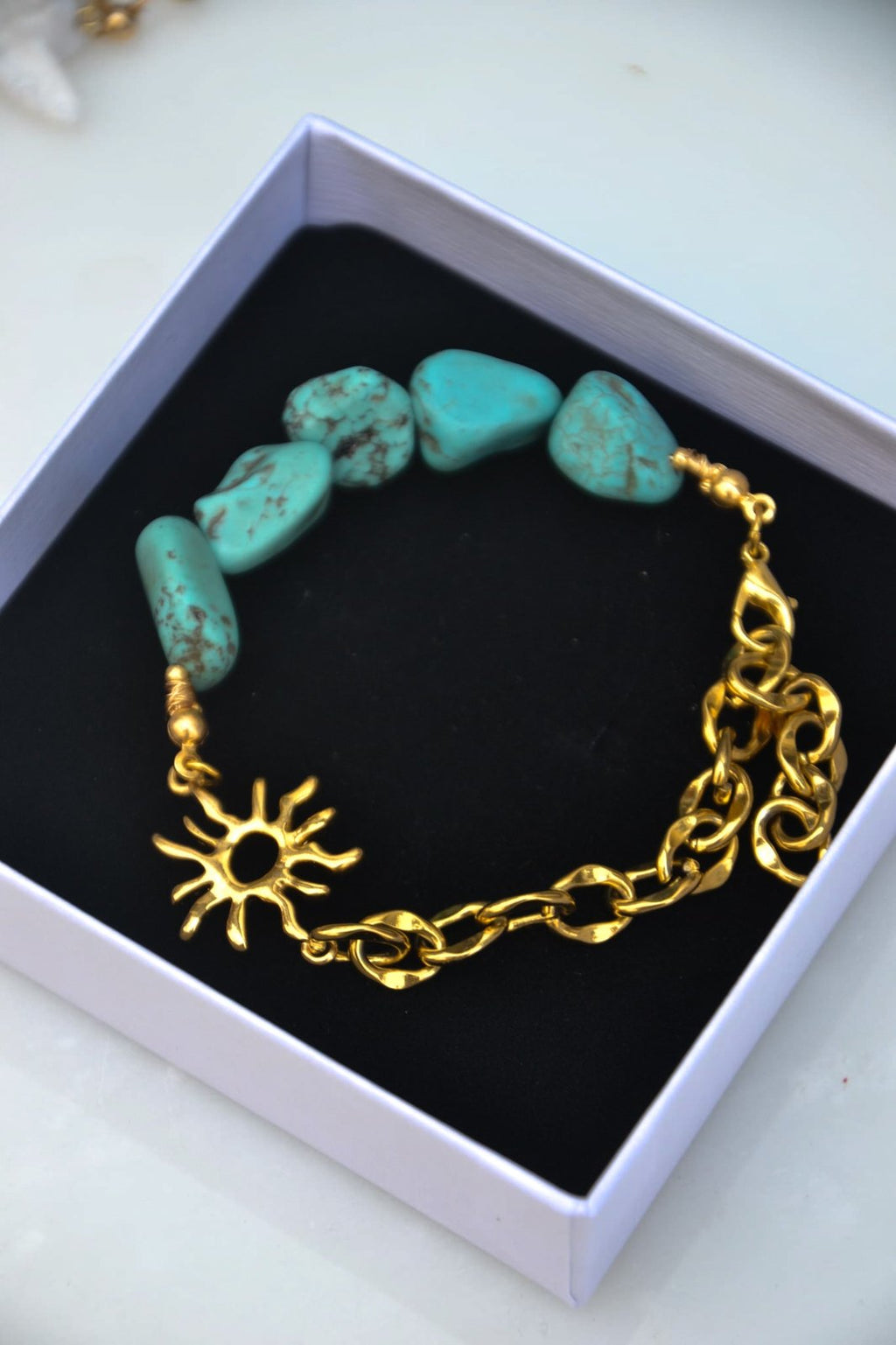Bracelet Aélios – Turquoise Naturelle, Soleil Doré &amp; Chaîne

Inspiré du dieu grec du Soleil, "Aélios" est un bracelet lumineux qui unit la chaleur dorée du soleil à la fraîcheur vibrante de la turquoise naturelle. Mi-chaîne dorée, mi-pierres, il symbolise l’équilibre entre l’éclat solaire et l’énergie tellurique de la terre.

La turquoise, pierre de protection et d’apaisement, évoque les eaux claires, les étés infinis et les esprits libres. Le motif soleil en métal doré ajoute une touche sacrée et rayon