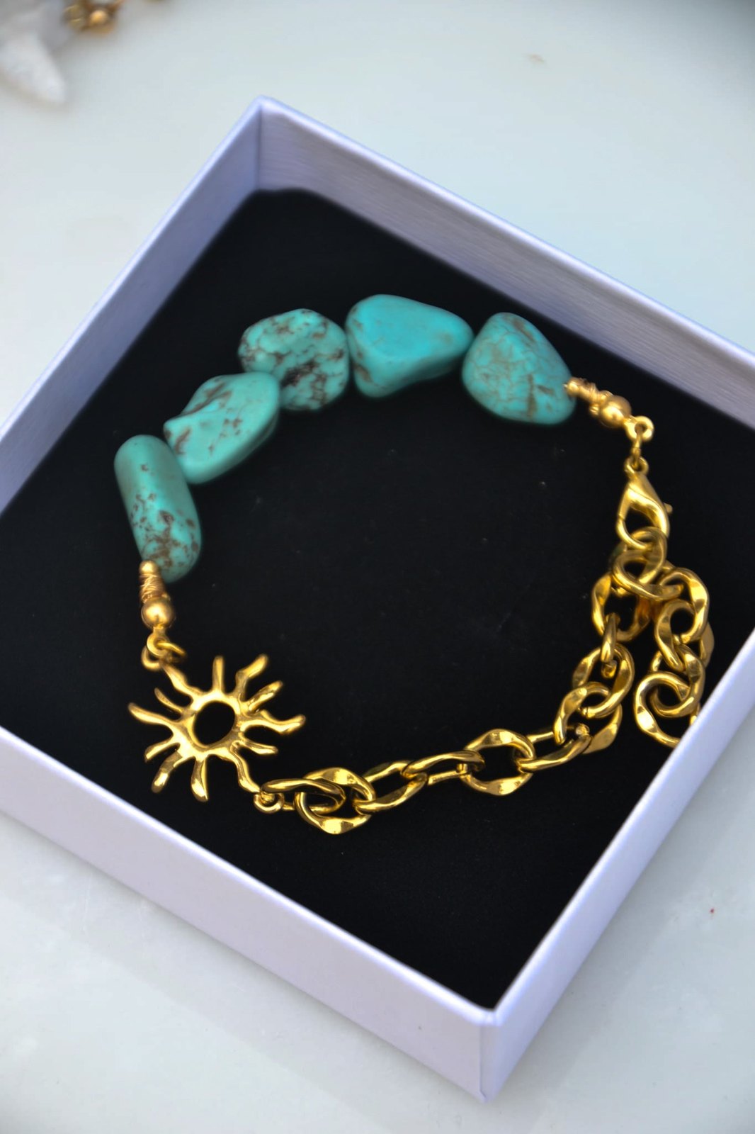 Bracelet Aélios – Turquoise Naturelle, Soleil Doré &amp; Chaîne

Inspiré du dieu grec du Soleil, "Aélios" est un bracelet lumineux qui unit la chaleur dorée du soleil à la fraîcheur vibrante de la turquoise naturelle. Mi-chaîne dorée, mi-pierres, il symbolise l’équilibre entre l’éclat solaire et l’énergie tellurique de la terre.

La turquoise, pierre de protection et d’apaisement, évoque les eaux claires, les étés infinis et les esprits libres. Le motif soleil en métal doré ajoute une touche sacrée et rayon