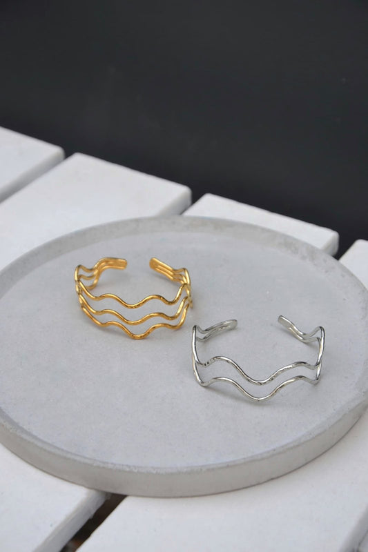 Le Jonc Amphitrite incarne la grâce et la puissance des vagues, symbolisant l'énergie éternelle de l’océan. Composé de quadruples ondulations harmonieuses, ce bijou est un hommage à la déesse Amphitrite, souveraine des eaux dans la mythologie grecque. Son design fluide et raffiné évoque la beauté intemporelle des flots, un équilibre parfait entre mouvement et sérénité.