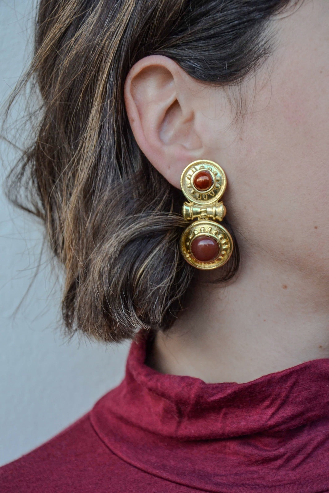 Boucles d'oreilles pendantes, plaquées or,en forme de bouclier, faites main par nos artisans.La divinité des festivités et de la floraison.Clips pour oreilles non percées