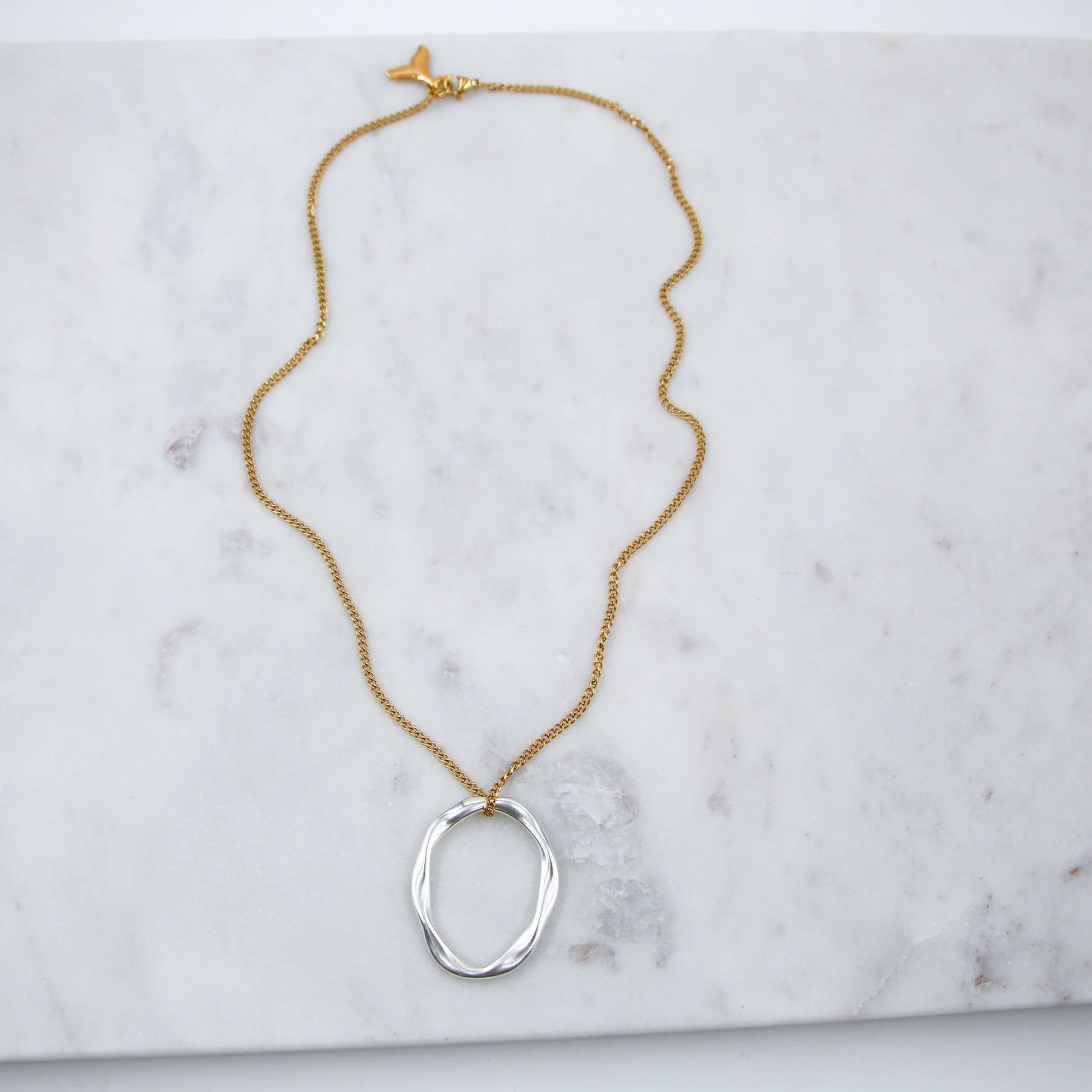 Le collier Kiklos est une pièce élégante qui allie la brillance de l'argent et la chaleur de l'or pour un look moderne et sophistiqué. Inspiré du mot grec "κύκλος" (kiklos) signifiant "cercle", ce collier met en avant des motifs circulaires harmonieux, représentant l’éternité et la complétude. Les éléments en argent et en or se juxtaposent ou s’entrelacent, créant un contraste subtil mais captivant.