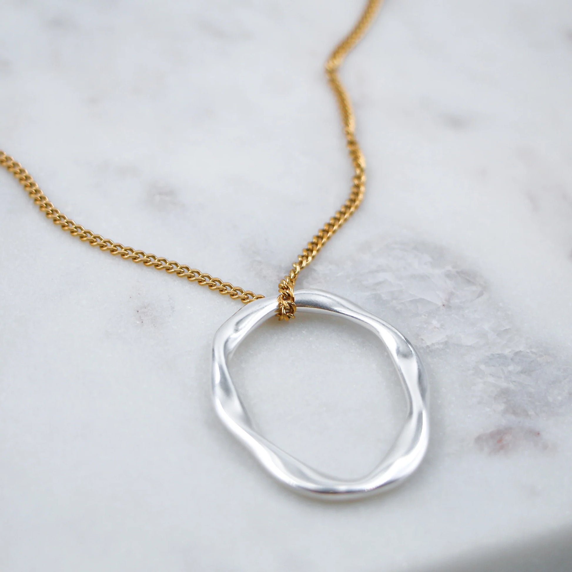 Le collier Kiklos est une pièce élégante qui allie la brillance de l'argent et la chaleur de l'or pour un look moderne et sophistiqué. Inspiré du mot grec "κύκλος" (kiklos) signifiant "cercle", ce collier met en avant des motifs circulaires harmonieux, représentant l’éternité et la complétude. Les éléments en argent et en or se juxtaposent ou s’entrelacent, créant un contraste subtil mais captivant.