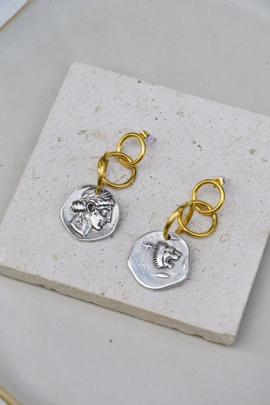 Boucles plaquées or, faites main par nos artisans.
Décorées d'une pièce de monnaie double face, à porter seul ou en superposition de boucles d'oreilles!